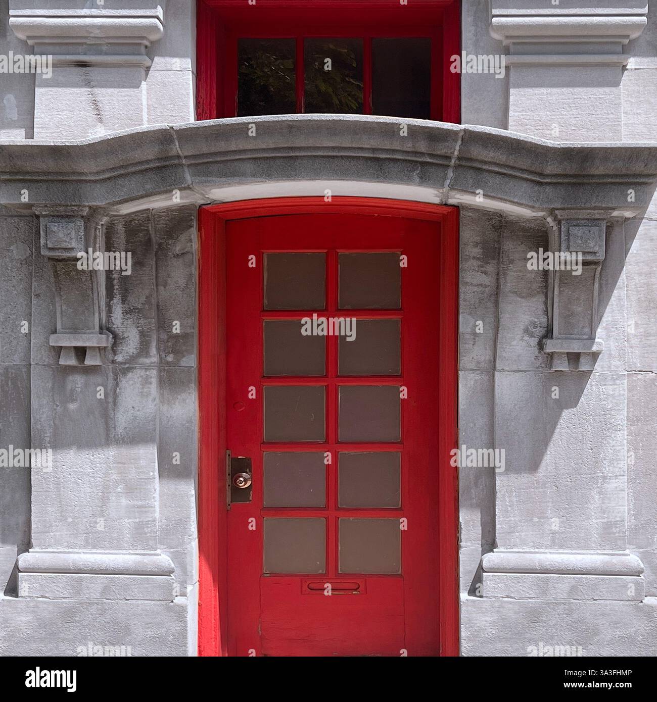 Red door with glass panels set within an ornate stone facade, blending historic and modern architectural elementsin Chicago - Smartphone Captured Stock Image