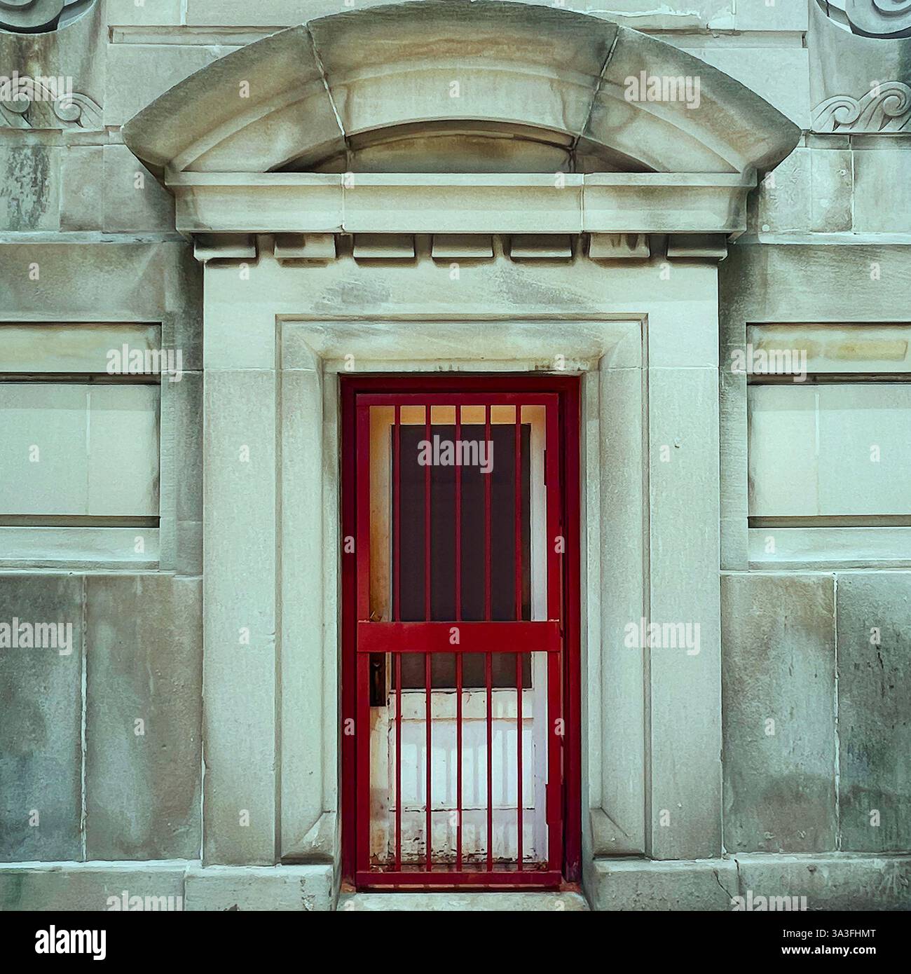Red-barred door set within a grand stone facade, showcasing classical architectural details and weathered textures - Smartphone Captured Stock Image