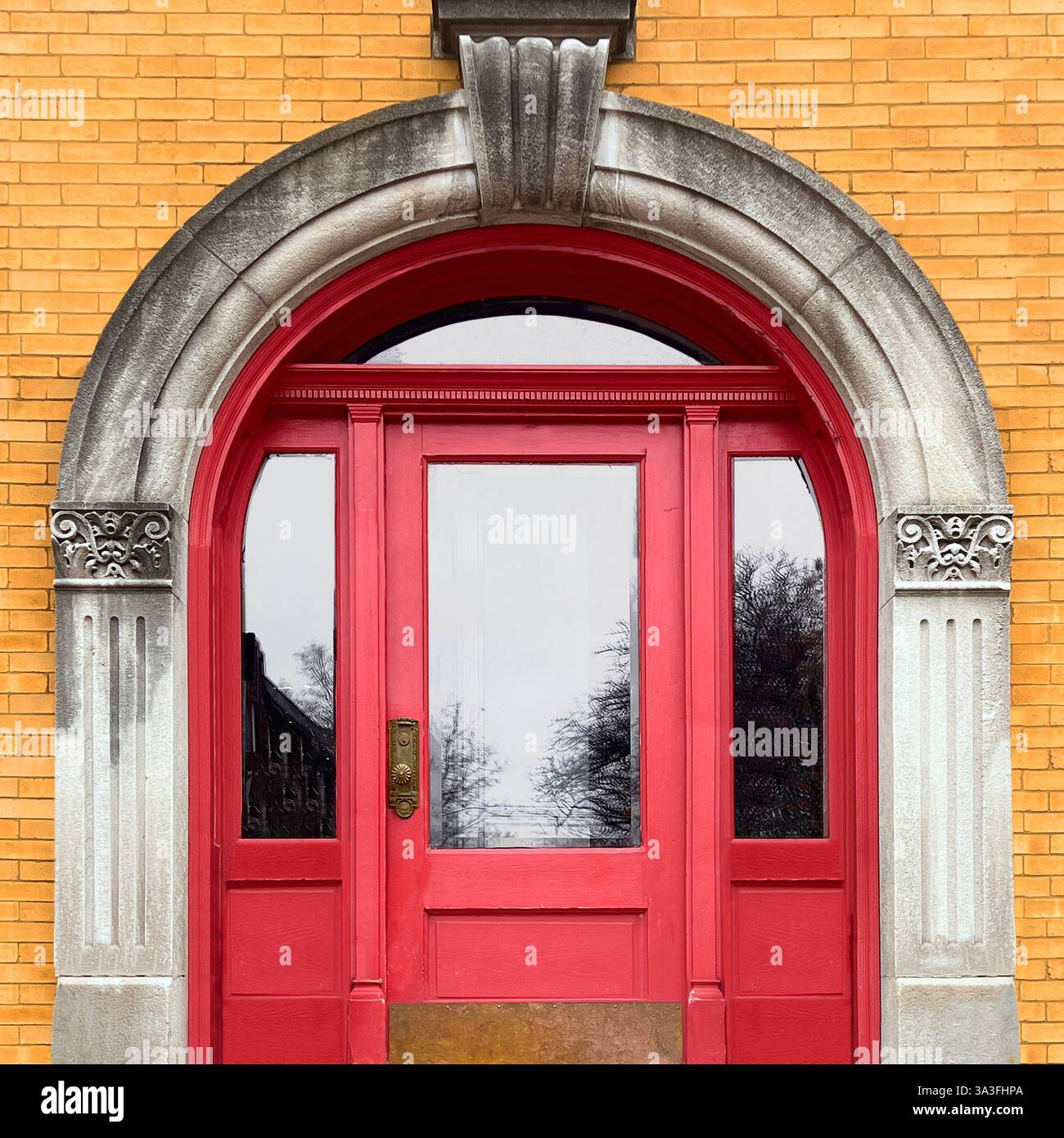 Elegant red arched doorway with intricate stone detailing, set against a yellow brick wall, showcasing historic architectural elements in Chicago. - Smartphone Captured Stock Image
