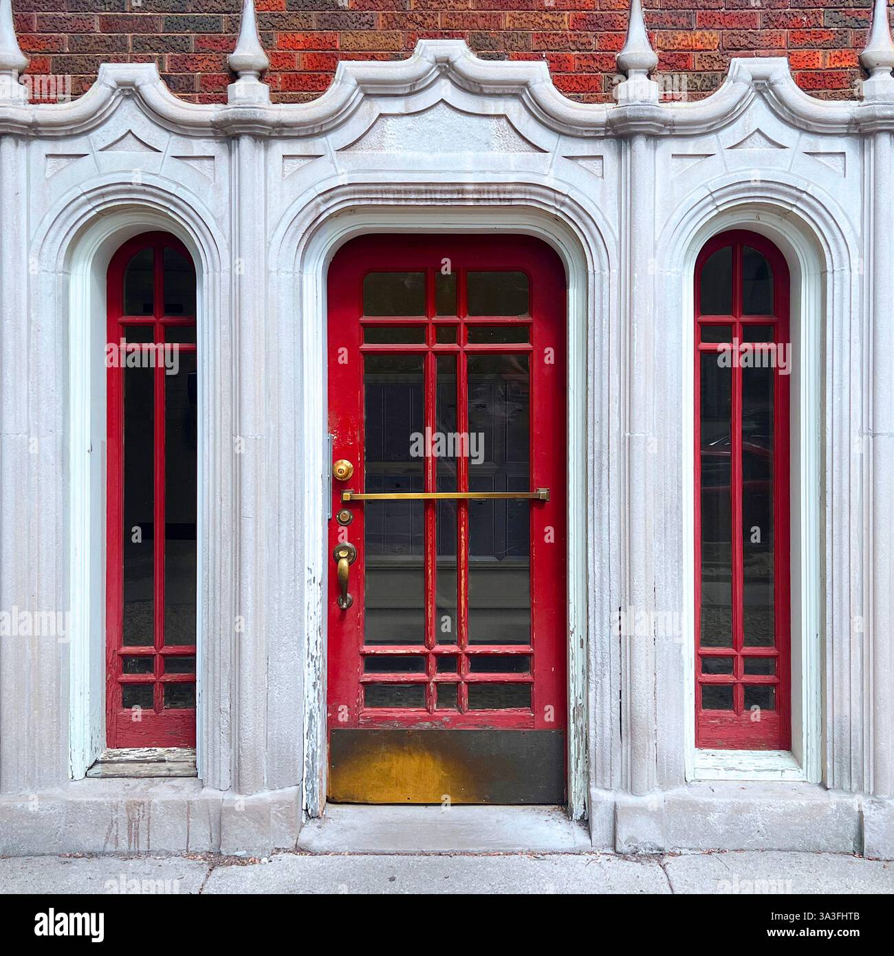 Gothic-style Red door with intricate glass panels, framed by ornate stone arches in Chicago - Smartphone Captured Stock Image