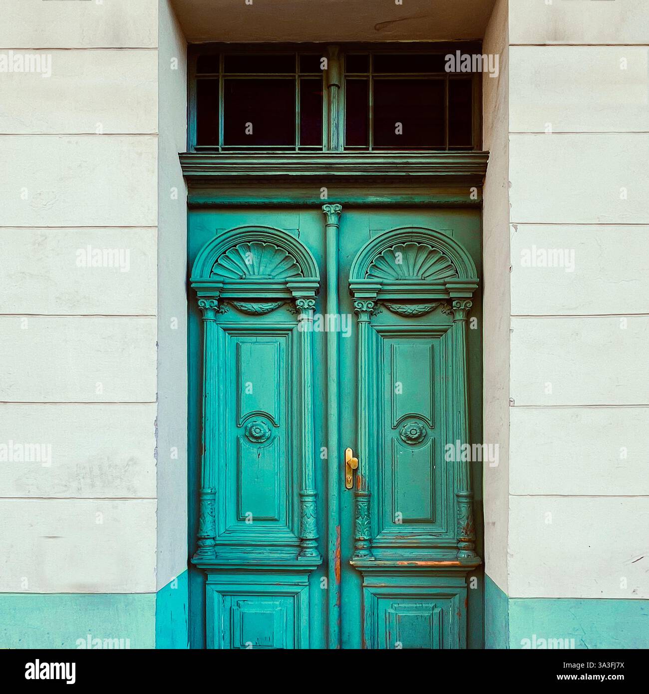 An ornate, turquoise double door with intricate carvings and shell motifs graces the entrance of a historic building in Kraków, Poland - Smartphone Captured Stock Image
