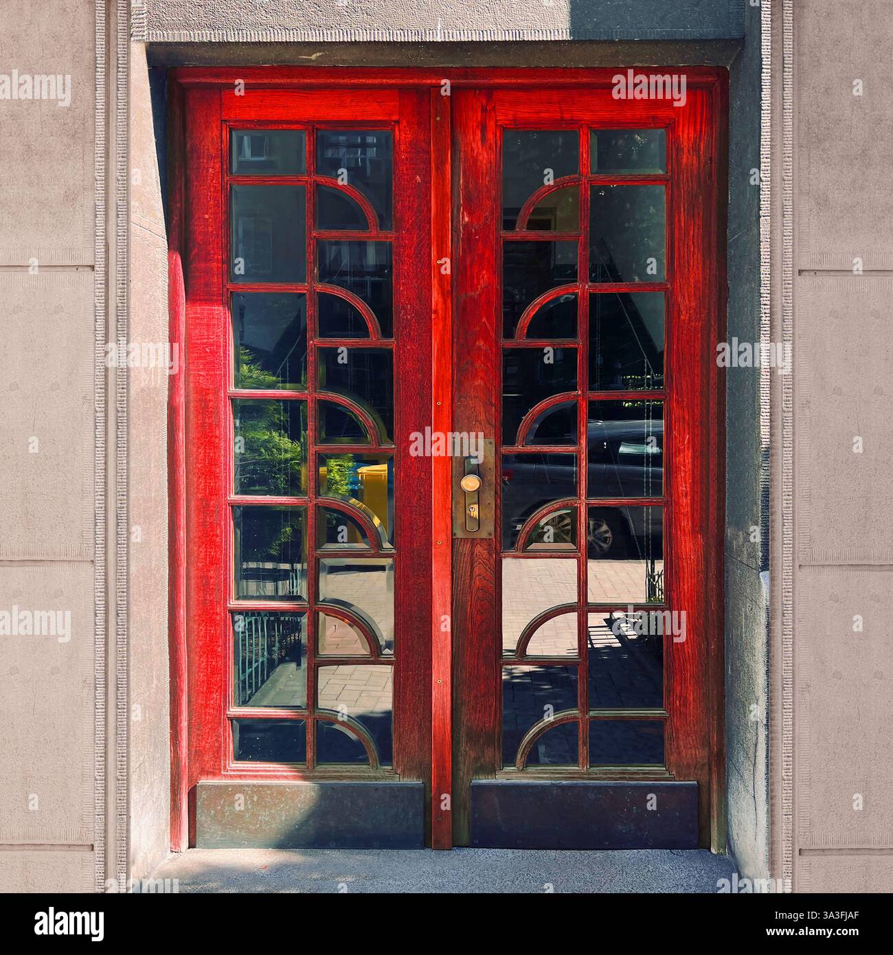 Elegant interwar modernist double doors in Krakow, Poland, featuring deep red wooden frames with geometric glass paneling - Smartphone Captured Stock Image