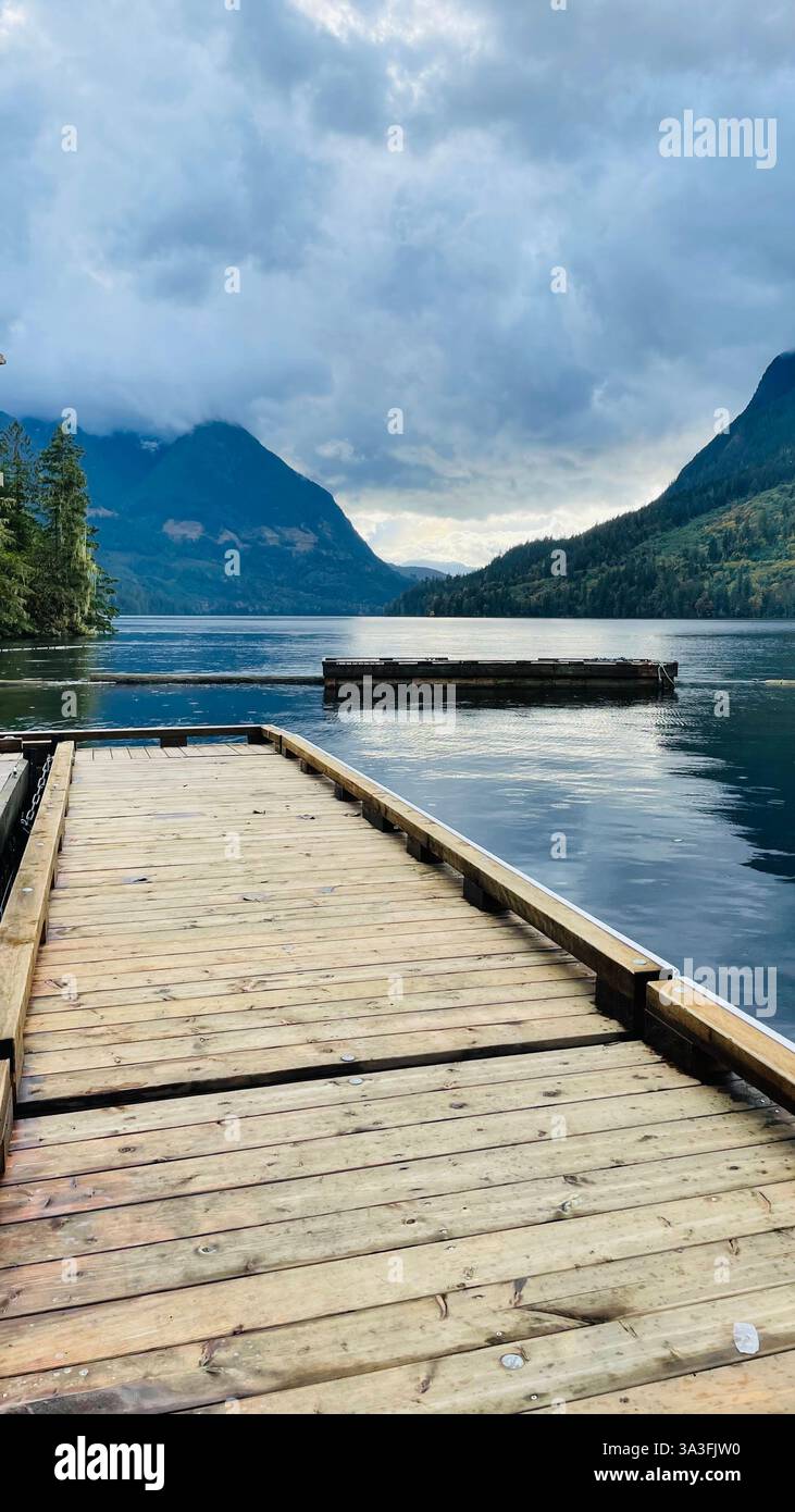 deck/bridge on the water with blue river and green mountains in the background with a sky full of clouds sunshine coast, bc, canada - Smartphone Captured Stock Image