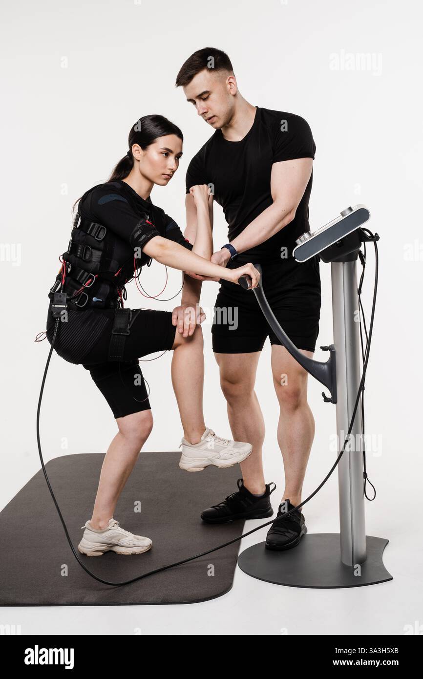 EMS sport training in electrical muscle stimulation suit. Man and girl ...