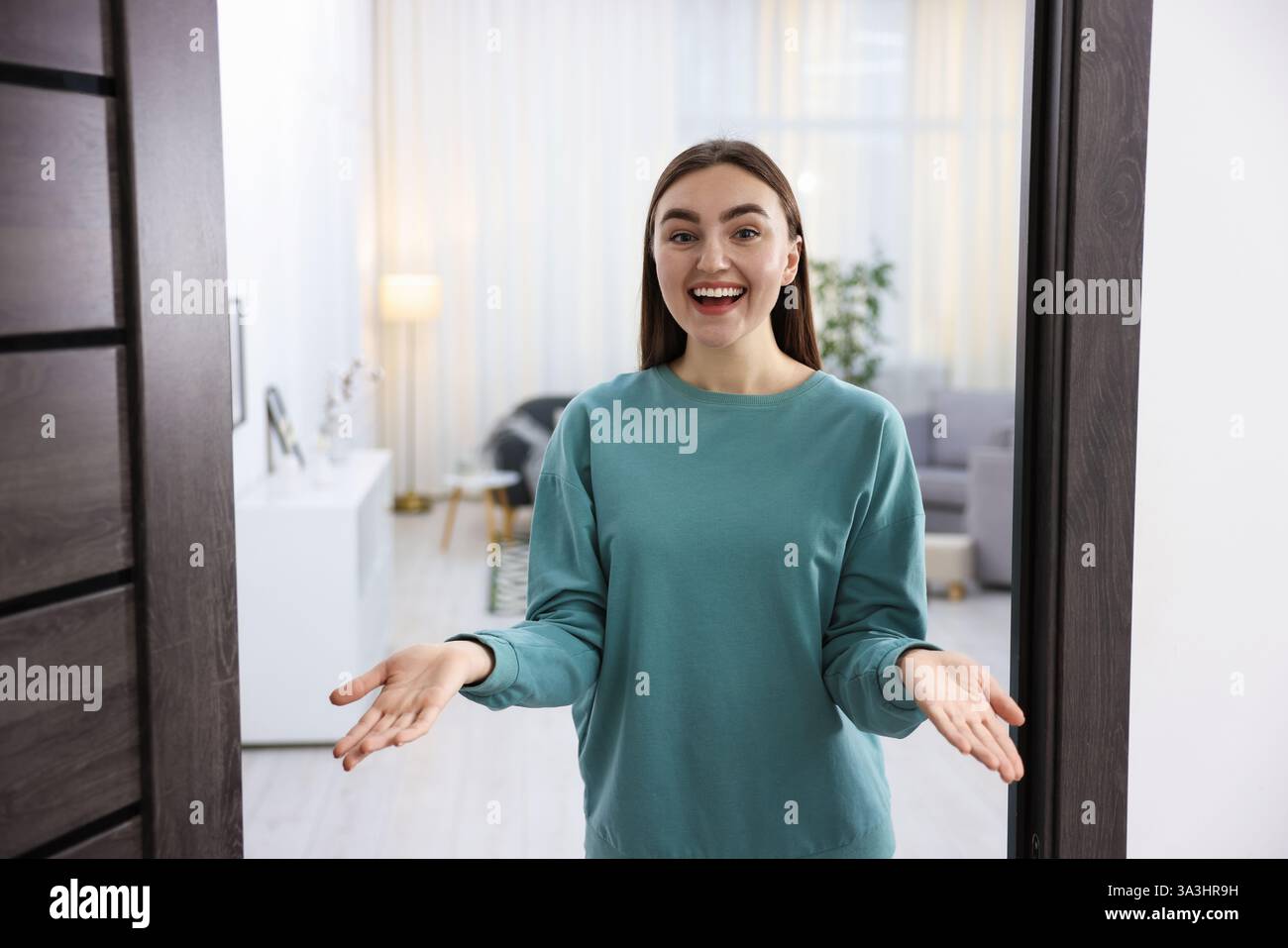 Cheerful woman welcoming guests to her apartment Stock Photo - Alamy