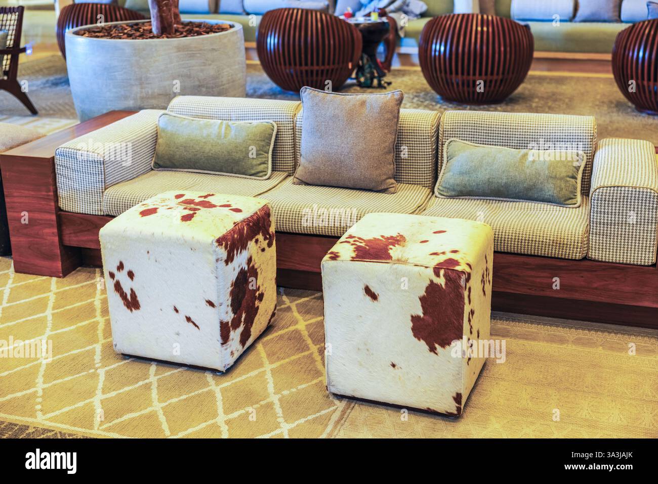 Luxury hotel lounge with stylish sofa, decorative pillows and two cube-shaped stools covered in cowhide. Mexico. Stock Photo