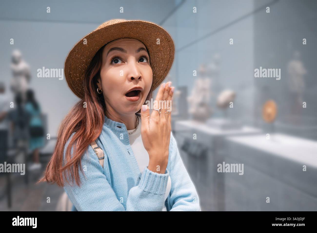Young woman yawning in a museum surrounded by historical exhibits. Bored visitor in an exhibition hall, expressing fatigue and disinterest Stock Photo
