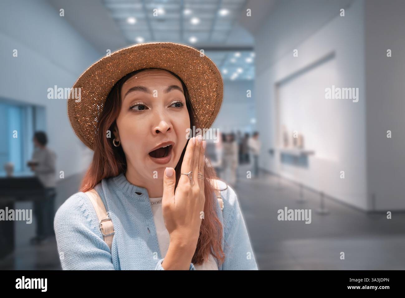 Young woman yawning in a museum surrounded by historical exhibits. Bored visitor in an exhibition hall, expressing fatigue and disinterest Stock Photo