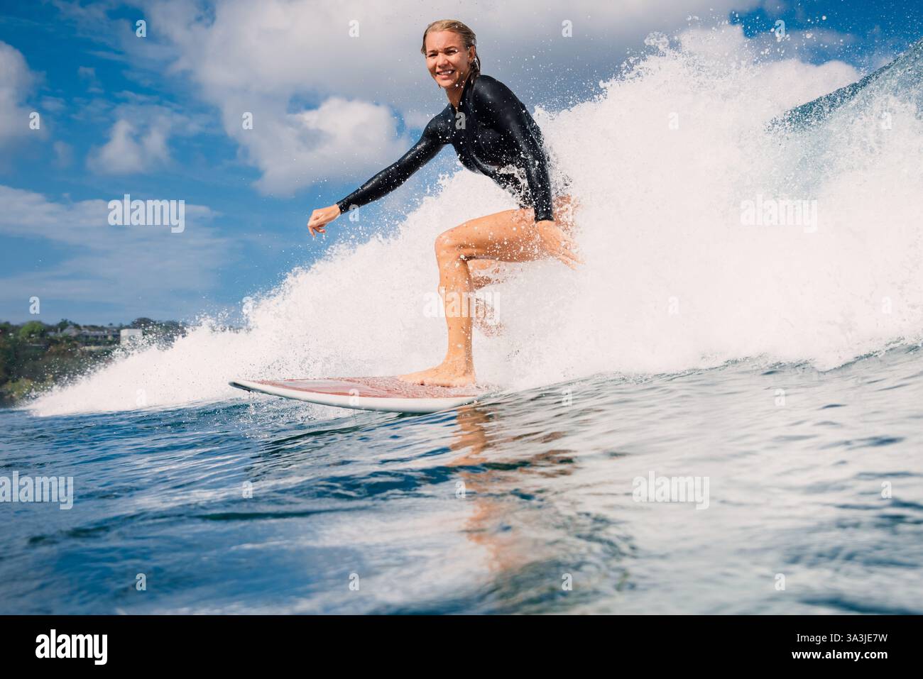 Female surfer riding a perfect breaking wave on a sunny day Stock Photo ...