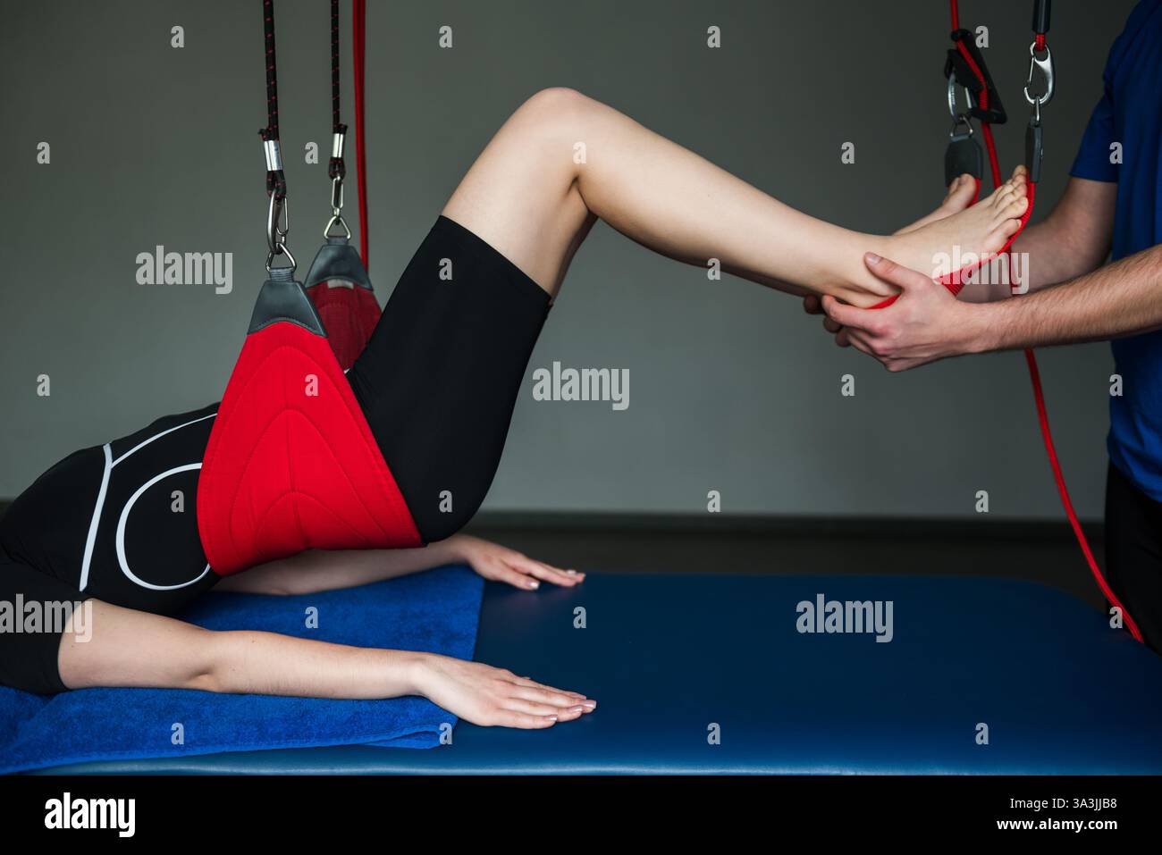 Girl legs is on red cord therapy to activate small muscles by relaxing ...