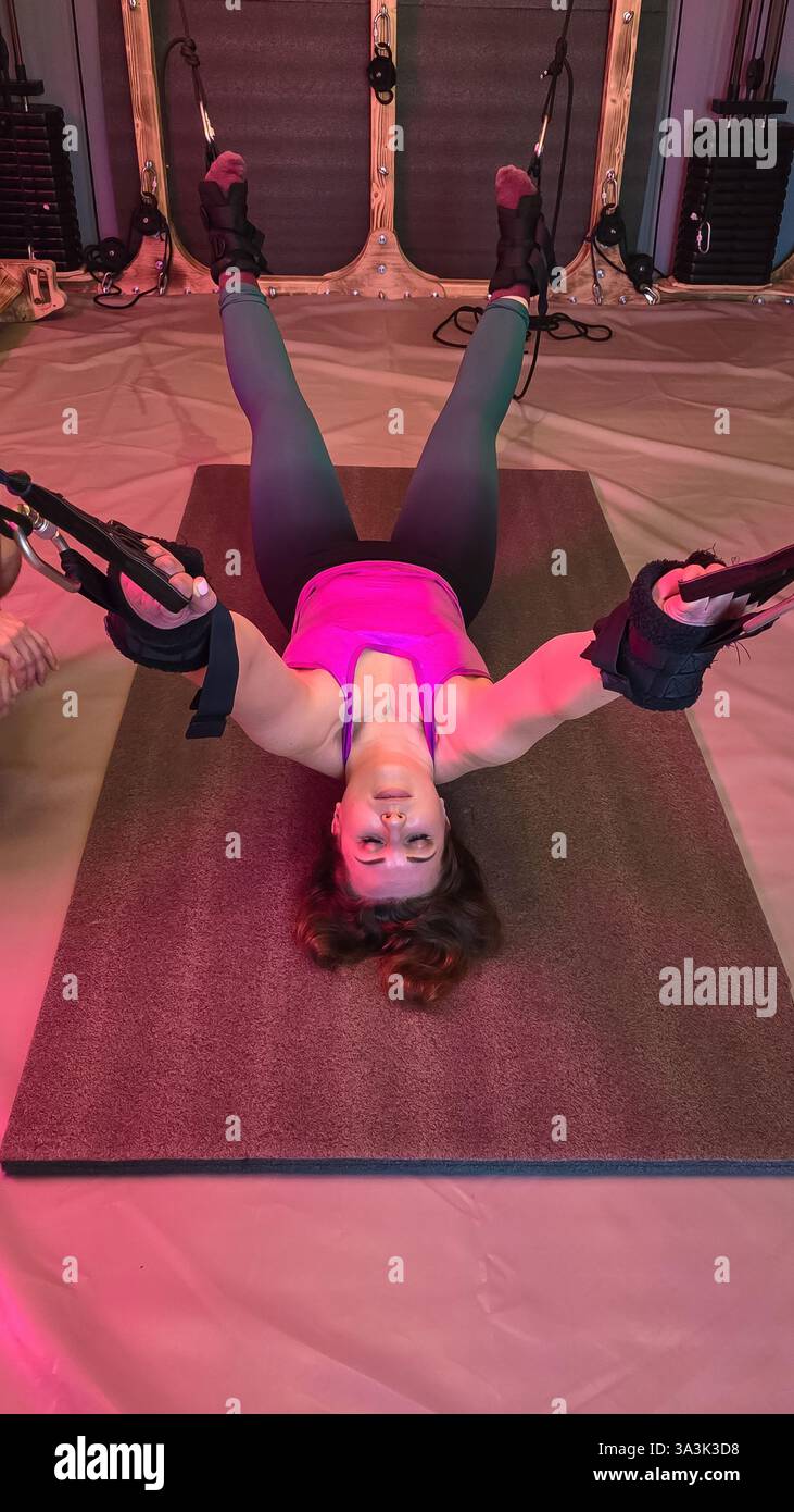 Woman is performing an inverted fly exercise using a suspension trainer ...