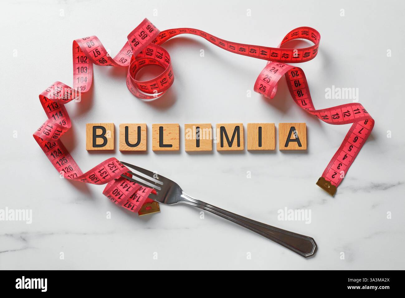 Word Bulimia, fork and measuring tape on white marble table, top view Stock Photo