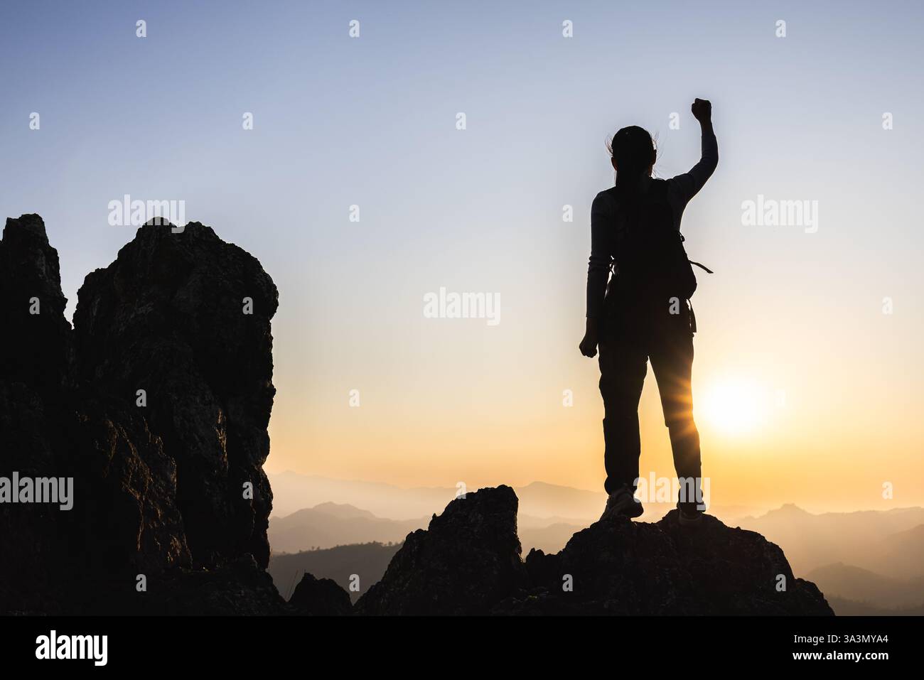 Silhouette of A person standing on top of the mountain with their arms ...