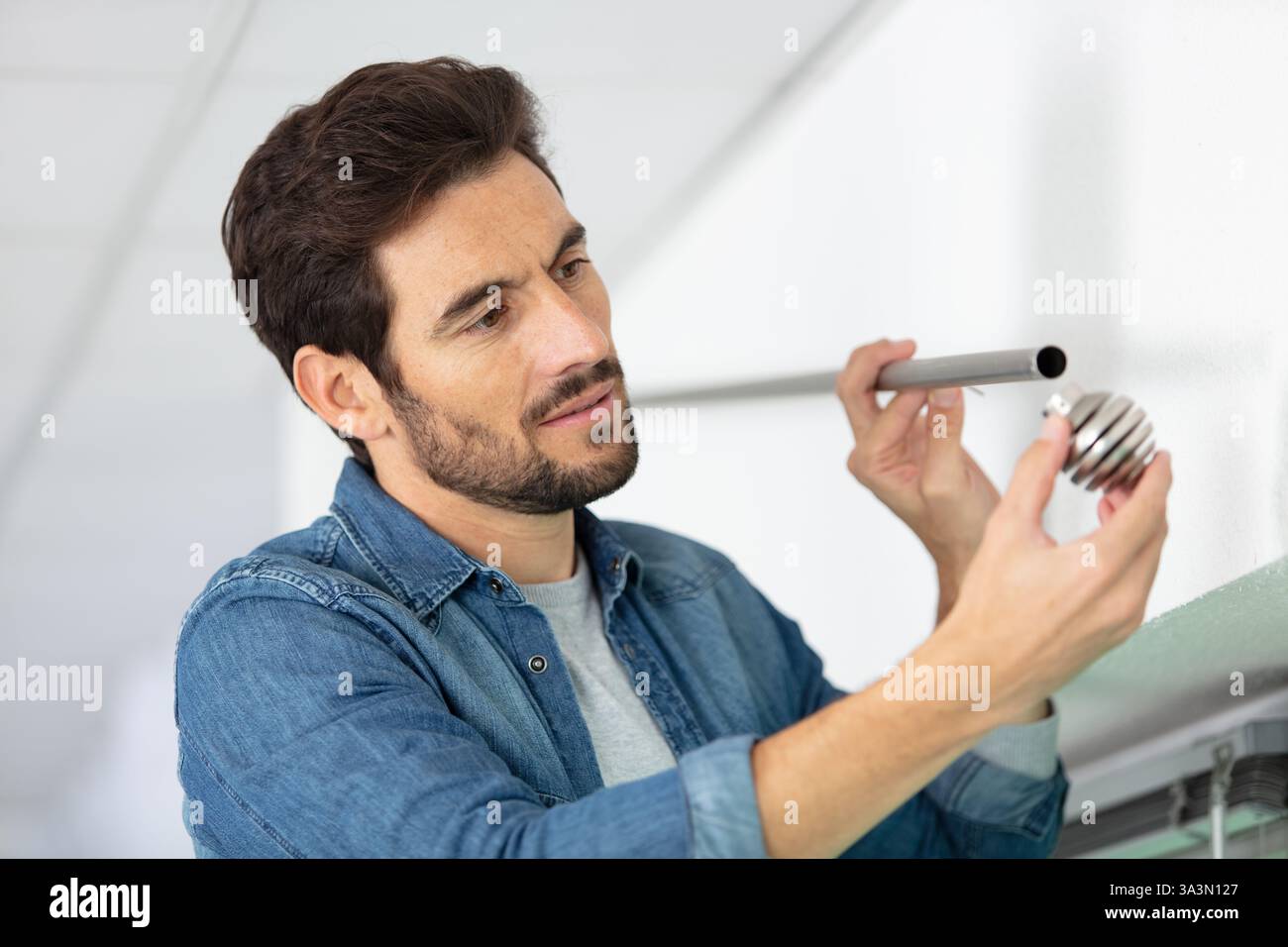 worker installing window curtain rod on the wall Stock Photo