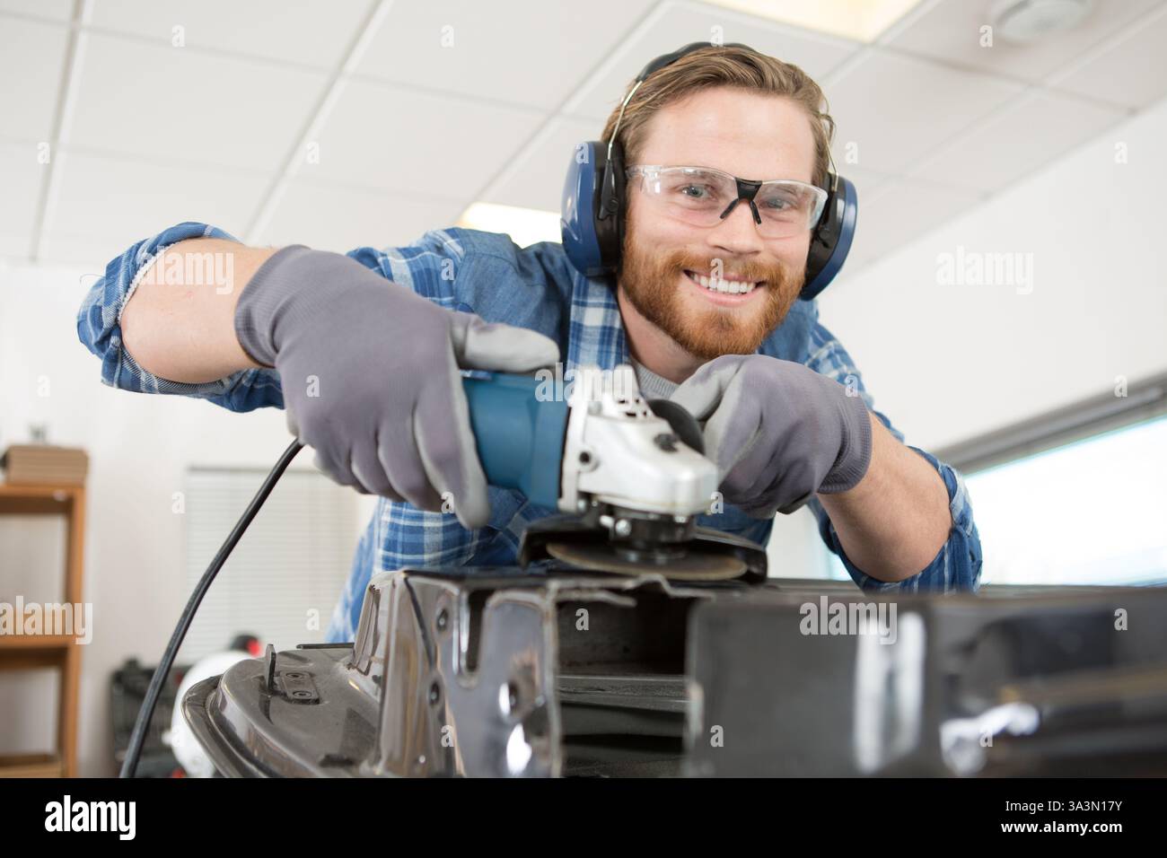 man using angle grinder in workshop Stock Photo