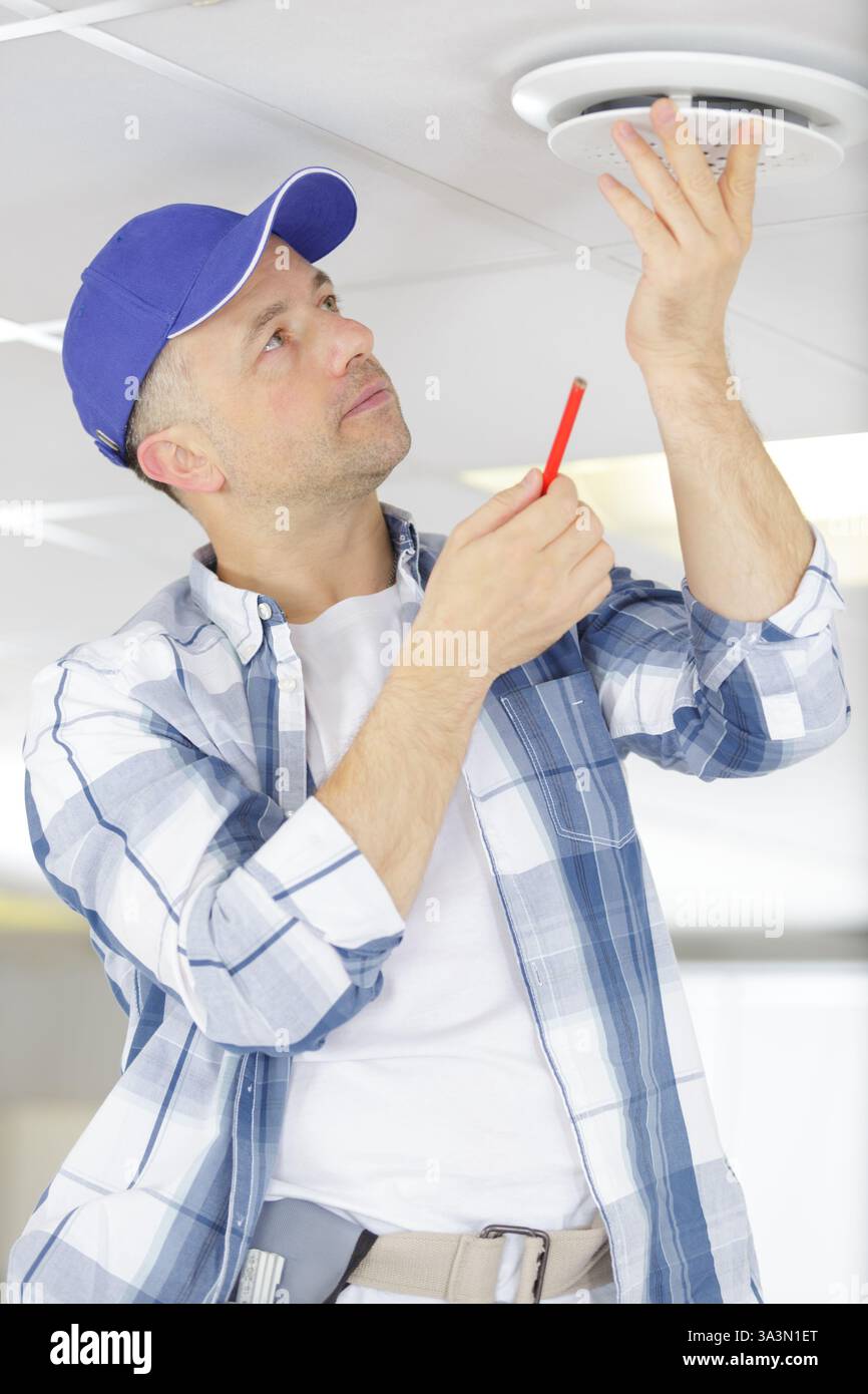 male technician installing ceiling fan Stock Photo