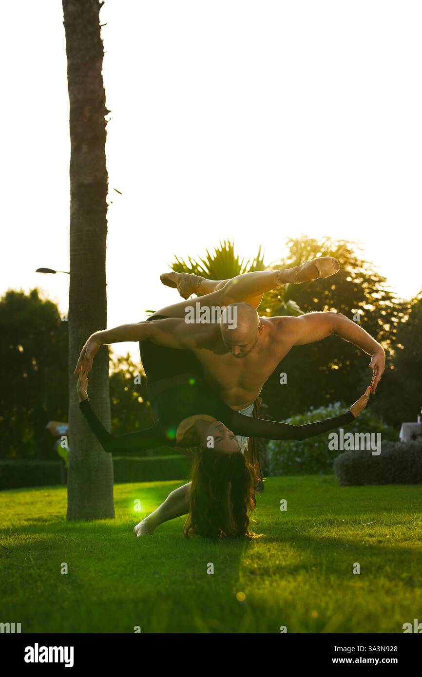 A man and a woman are gracefully performing acrobatics in a park Stock Photo