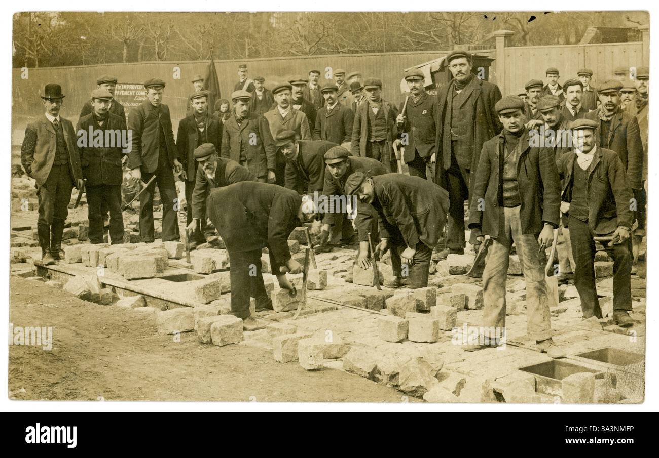 Edwardian era postcard of labourers working on laying paving blocks. 1900's working class men labouring outdoors. They are working for a company called The Improved Pavement Company Ltd , see sign, circa 1905, 1910  U.K. Stock Photo