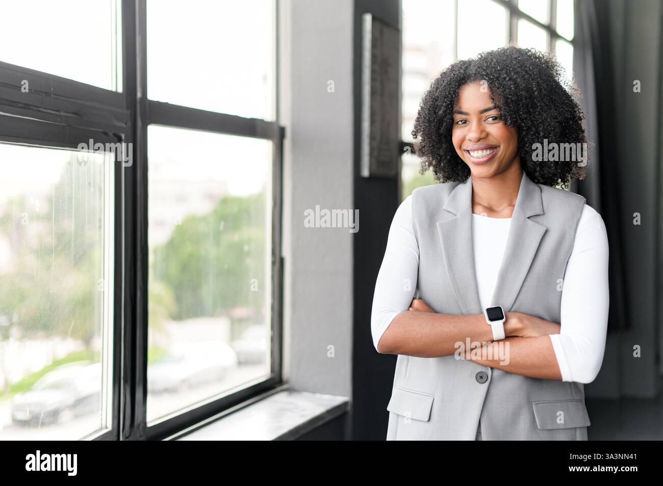 An African-American businesswoman stands with her arms crossed in a ...
