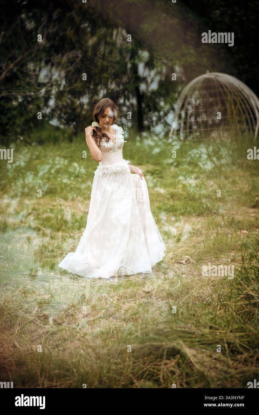 Stunning bride gracefully poses in a spring park, among blossoming trees. exuding elegance, Stock Photo