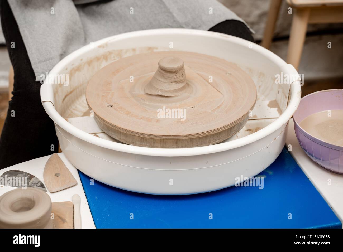 Clay in the center of pottery wheel to start forming the right size and ...