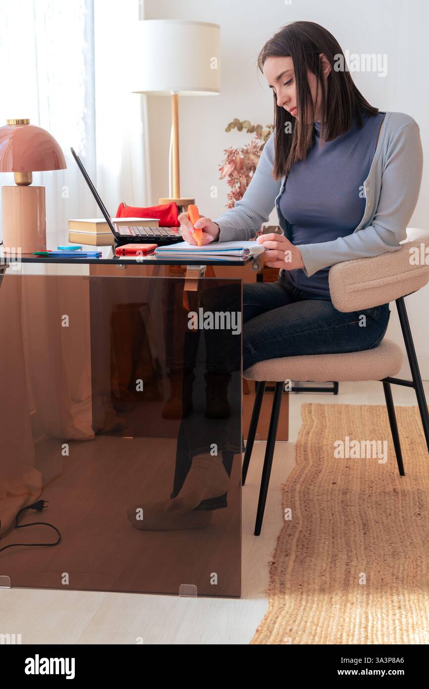 Caucasian smiling student studying at home, writing in notebook, using laptop Stock Photo