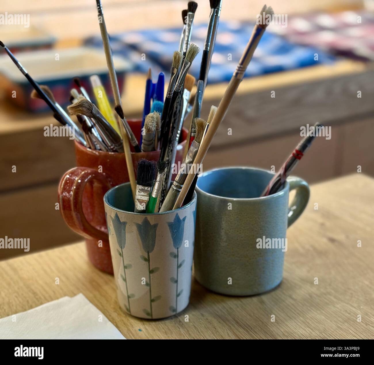 Artists Paintbrushes in a ceramic pot and mugs Stock Photo