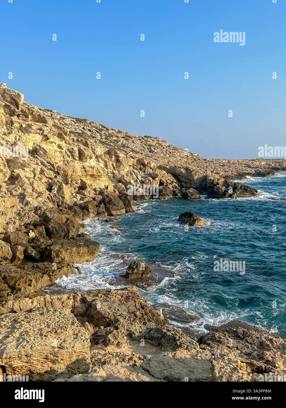 Majestic stone cliffs at Cape Greco, Cyprus, towering above the crystal-clear Mediterranean waters. A breathtaking natural wonder. - Smartphone Captured Stock Image