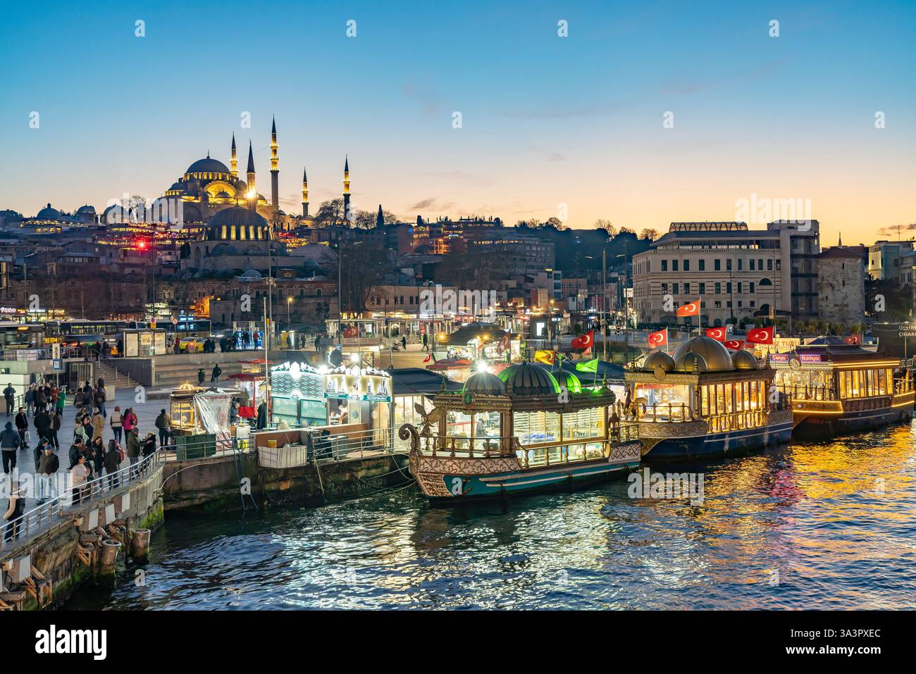Restaurantschiffe am Ufer von Eminönü, Rüstem-Pascha-Moschee und Süleymaniye-Moschee in der Abenddämmerung, Istanbul, Türkei  |   Restaurant Ships at Stock Photo
