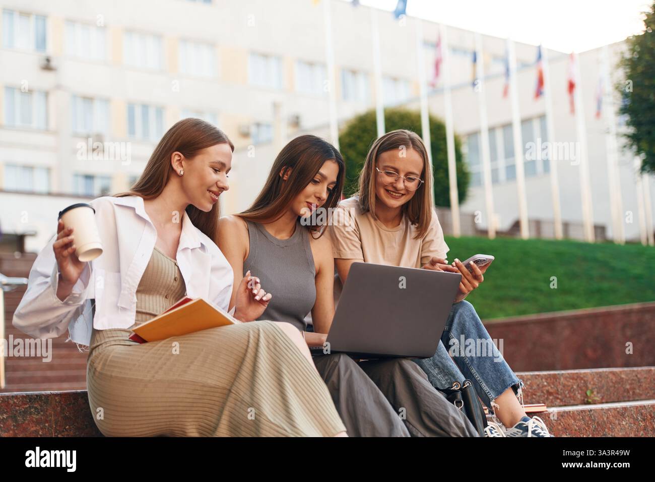 Learning, using laptop. Group of students are outside together. Stock Photo