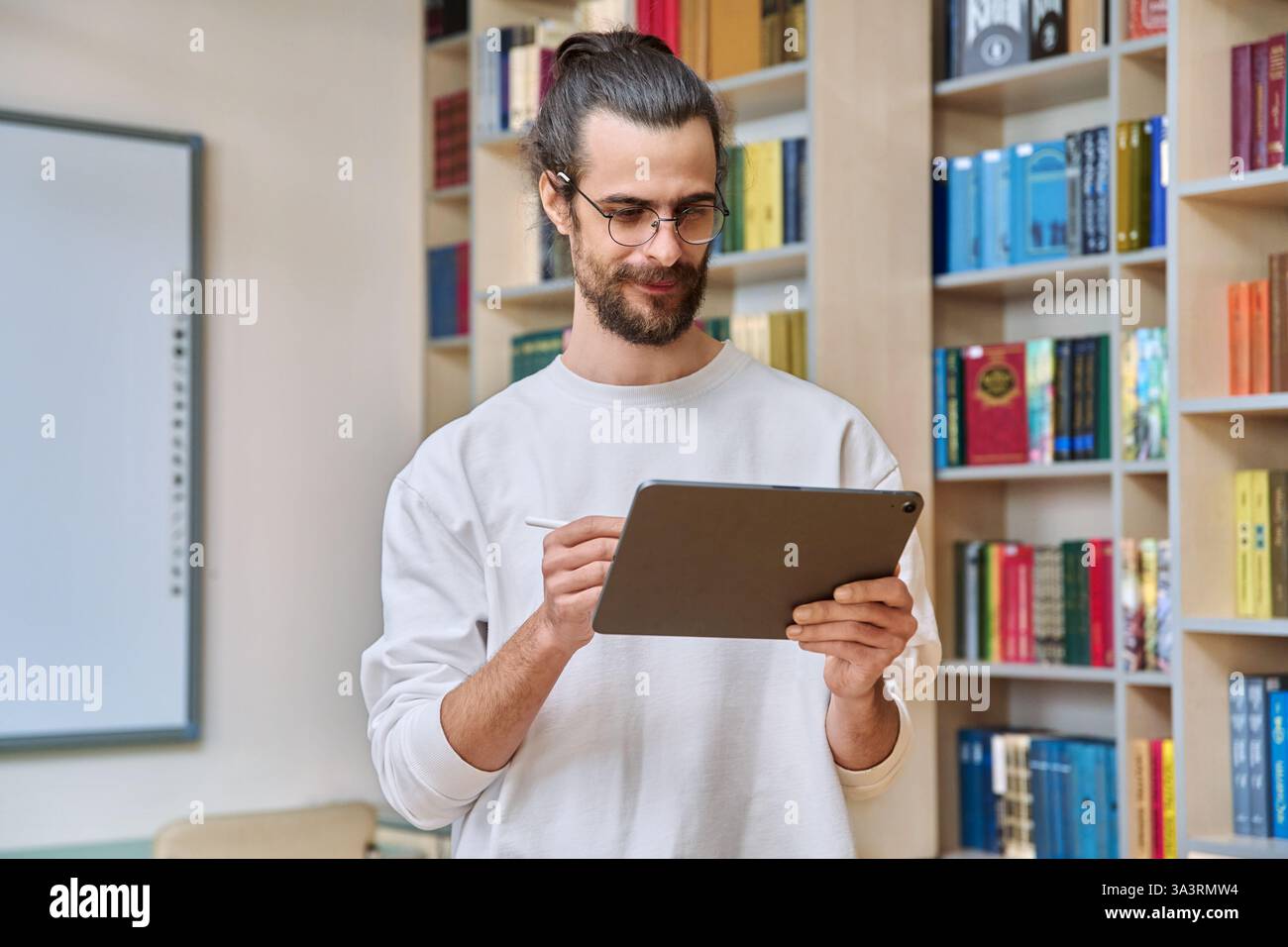 Young handsome man using digital tablet inside library office Stock Photo
