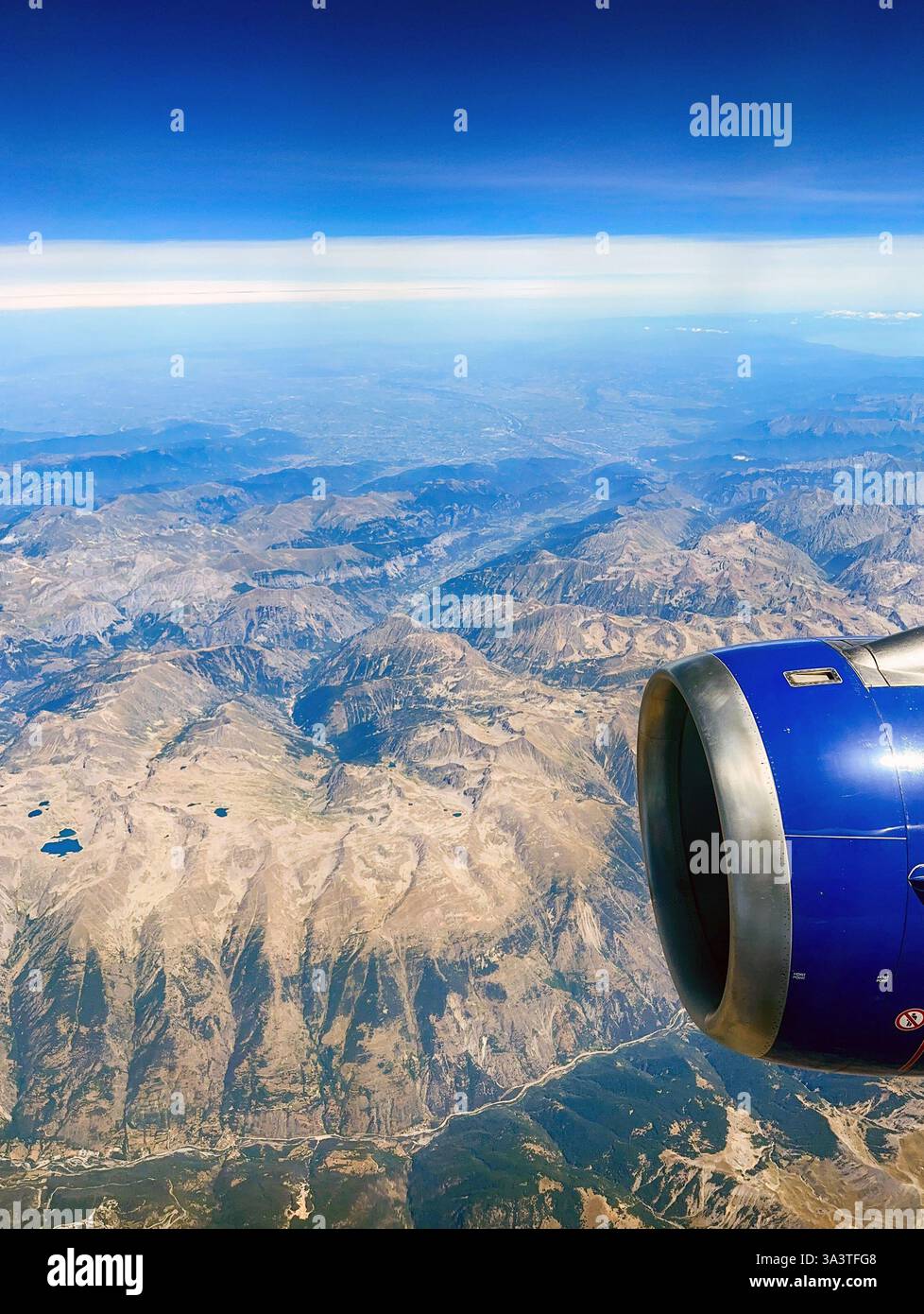 En route Malta to London - 9 August 2023: Scenic view of the Swiss Alps and a jet engine from a window seat in a holiday jet. - Smartphone Captured Stock Image