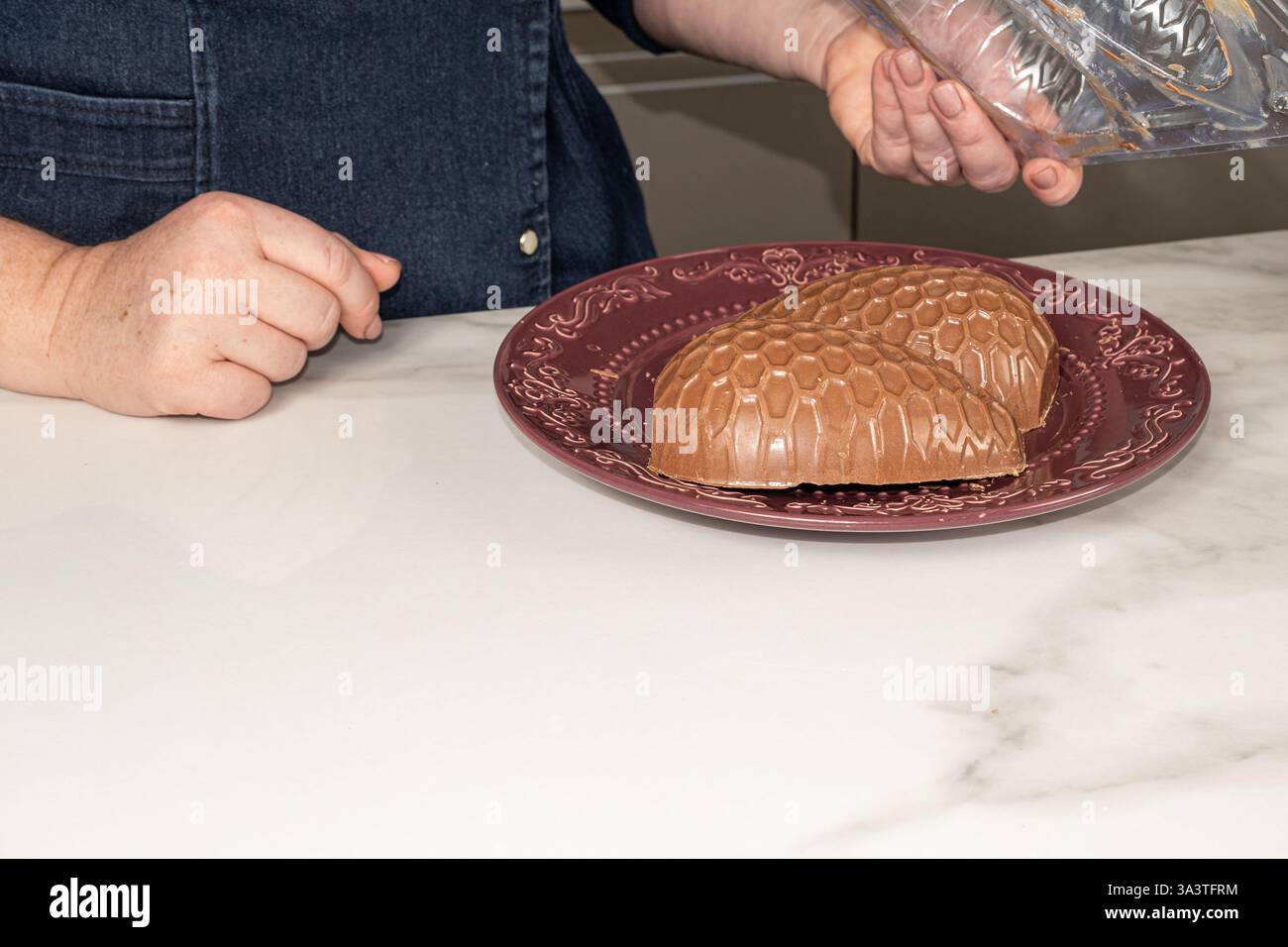Confectioner removing chocolate Easter egg mold. Stock Photo