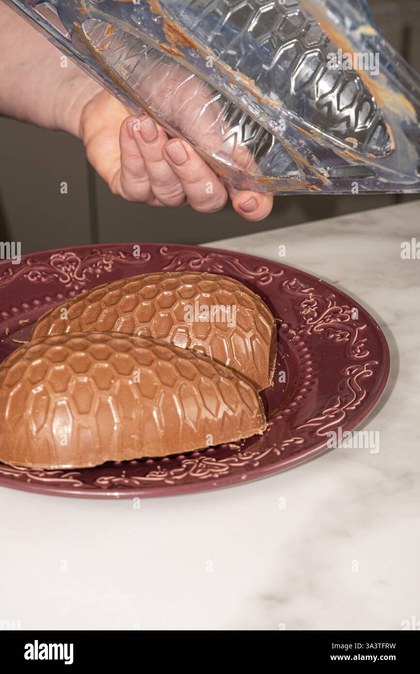 Confectioner removing chocolate Easter egg mold_vertical. Stock Photo