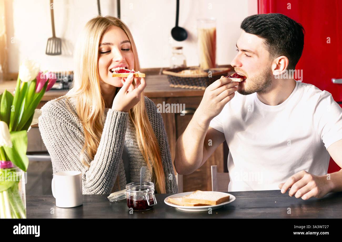 Couple enjoying breakfast together in a cozy kitchen with toast and jam Stock Photo