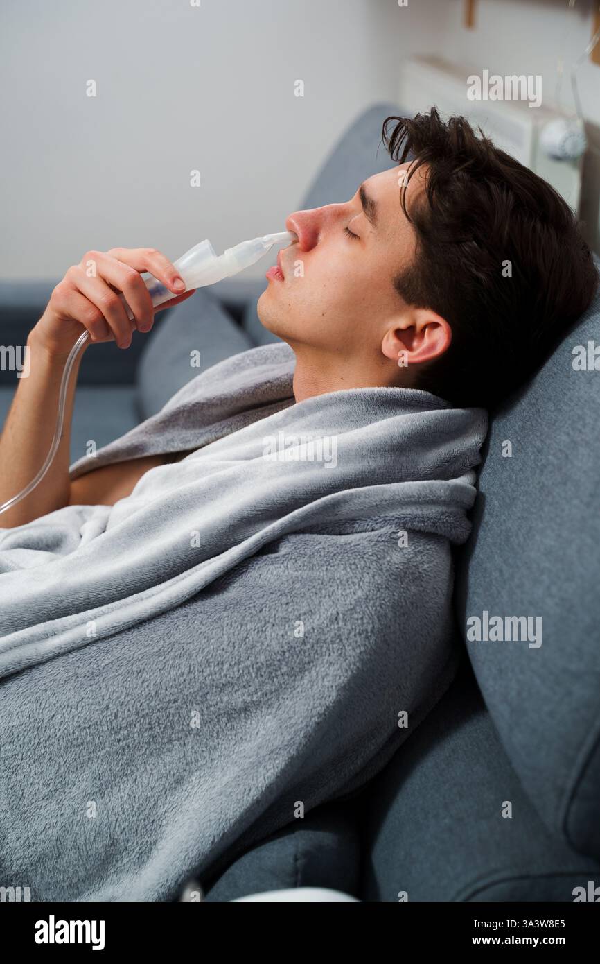 Young man with asthma attack breathing with inhaler in the bad. Doing ...