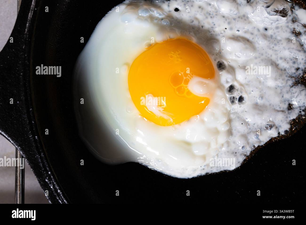 A fried egg, over easy in black cast iron pan Stock Photo