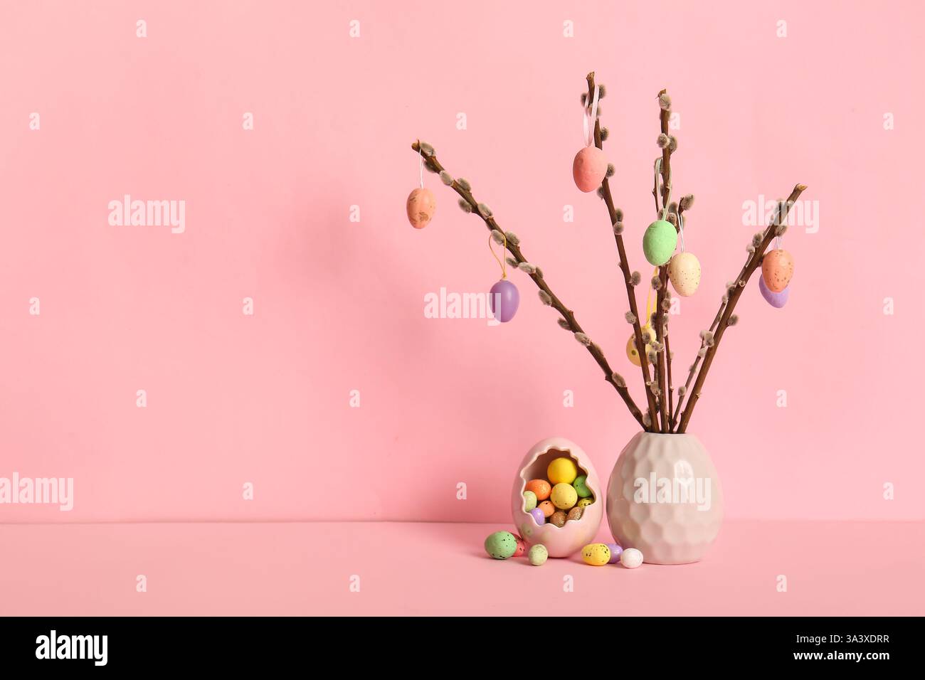 Vase with willow branches and colorful Easter eggs on yellow background Stock Photo
