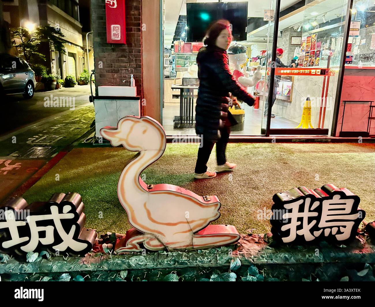 Taipei, Taiwan, Woman Walking in Front of Sign, Taiwanese Duck and Goose Restaurant, 'Acheng Goose', Street Scene at Night - Smartphone Captured Stock Image