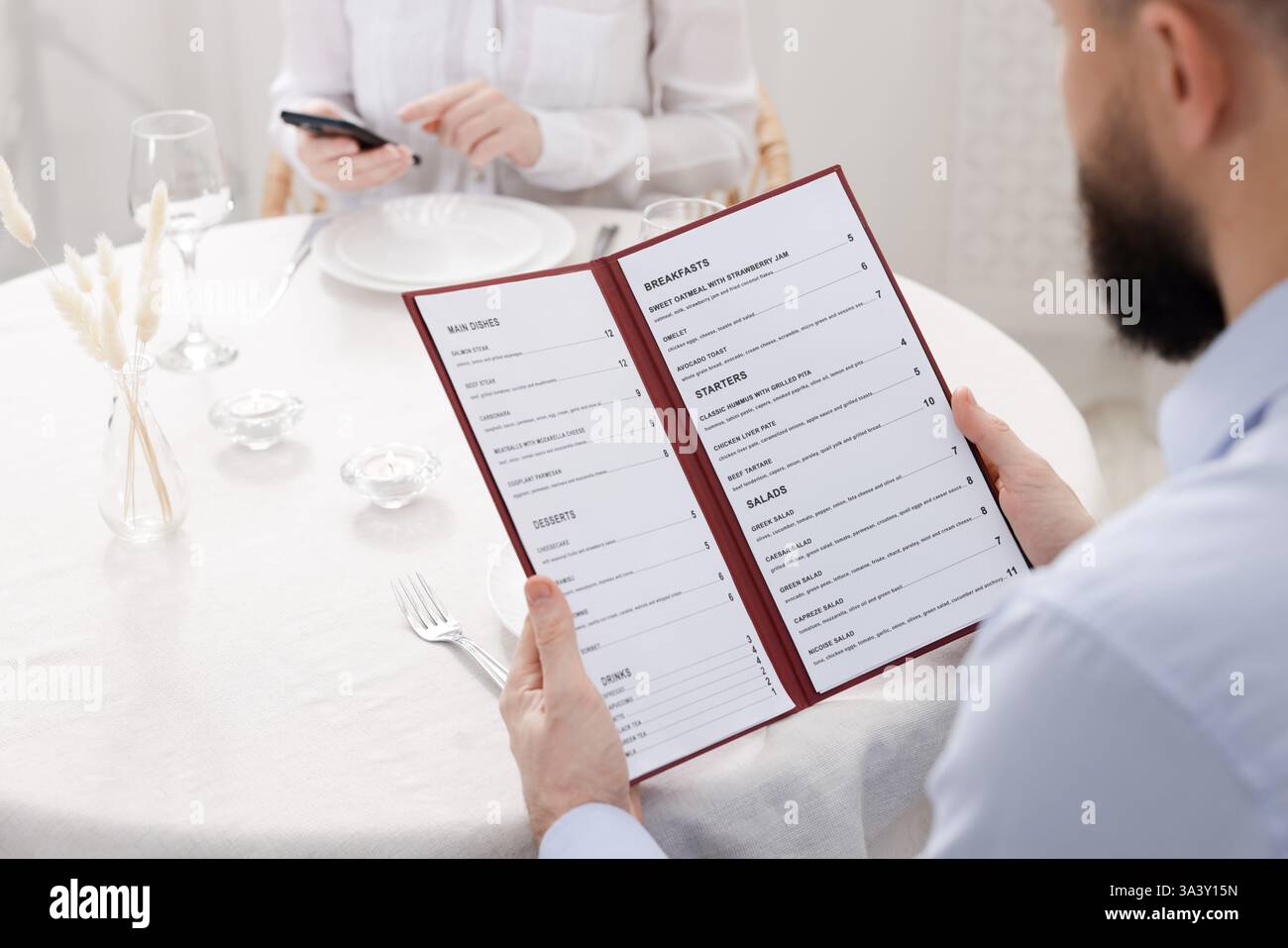 Man with menu at table in restaurant, closeup Stock Photo - Alamy