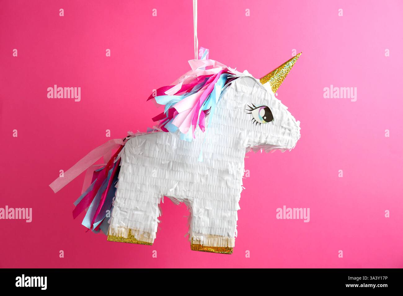 Bright pinata in shape of unicorn hanging on pink background Stock ...