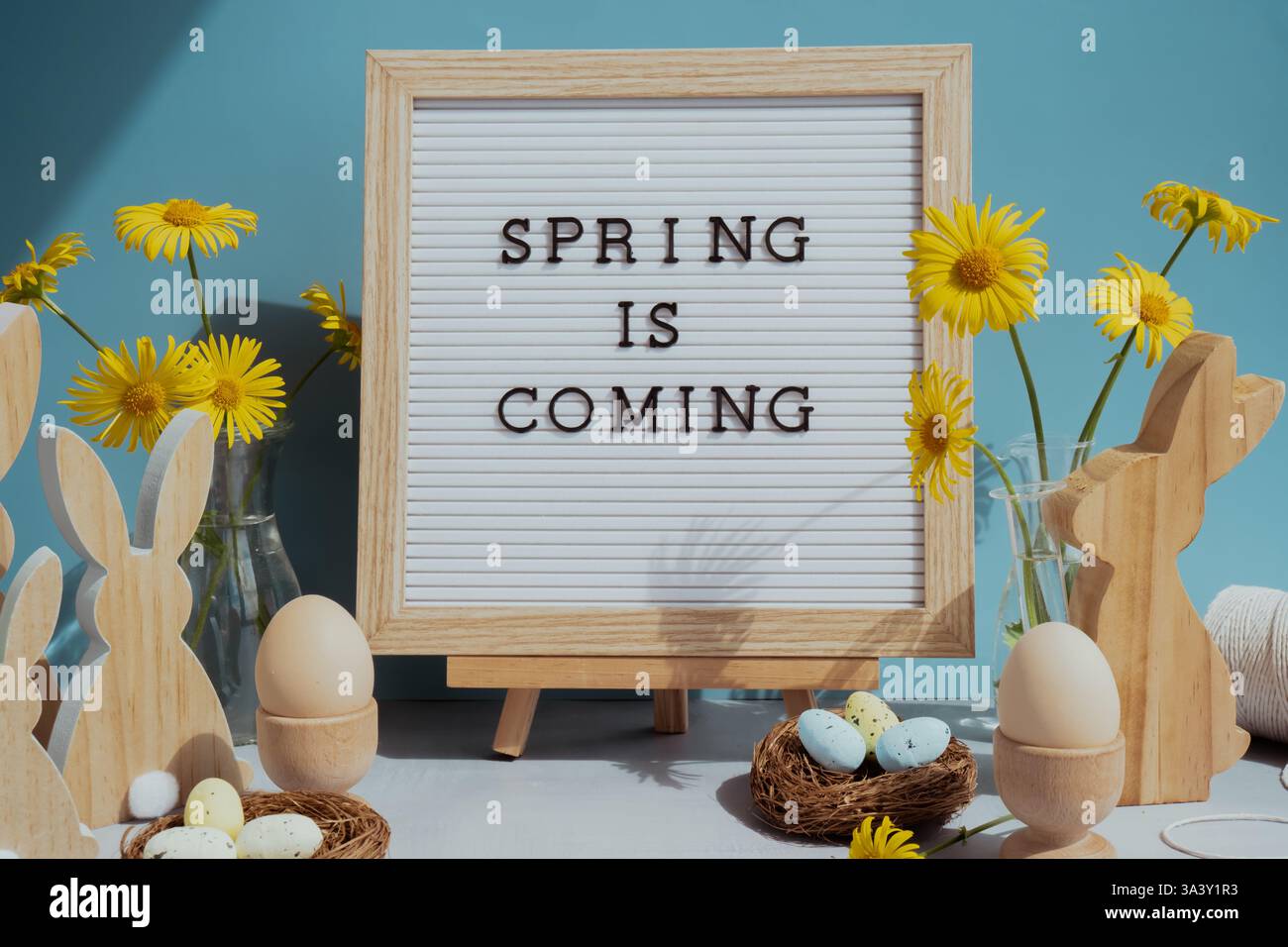 SPRING IS COMING text on letter board with bunny wooden figures and ...