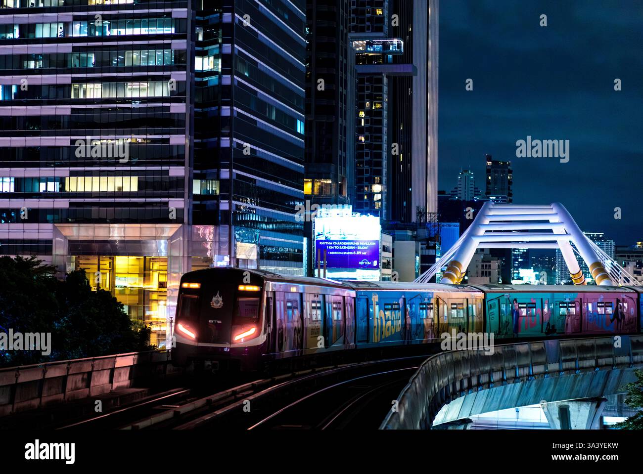 This vibrant nighttime image captures a BTS Skytrain moving through ...
