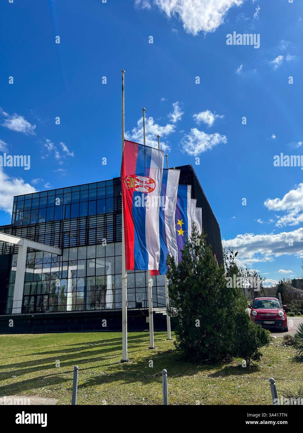 Serbian flags lowered to half-mast in honor of the Day of Mourning, symbolizing respect and remembrance. - Smartphone Captured Stock Image