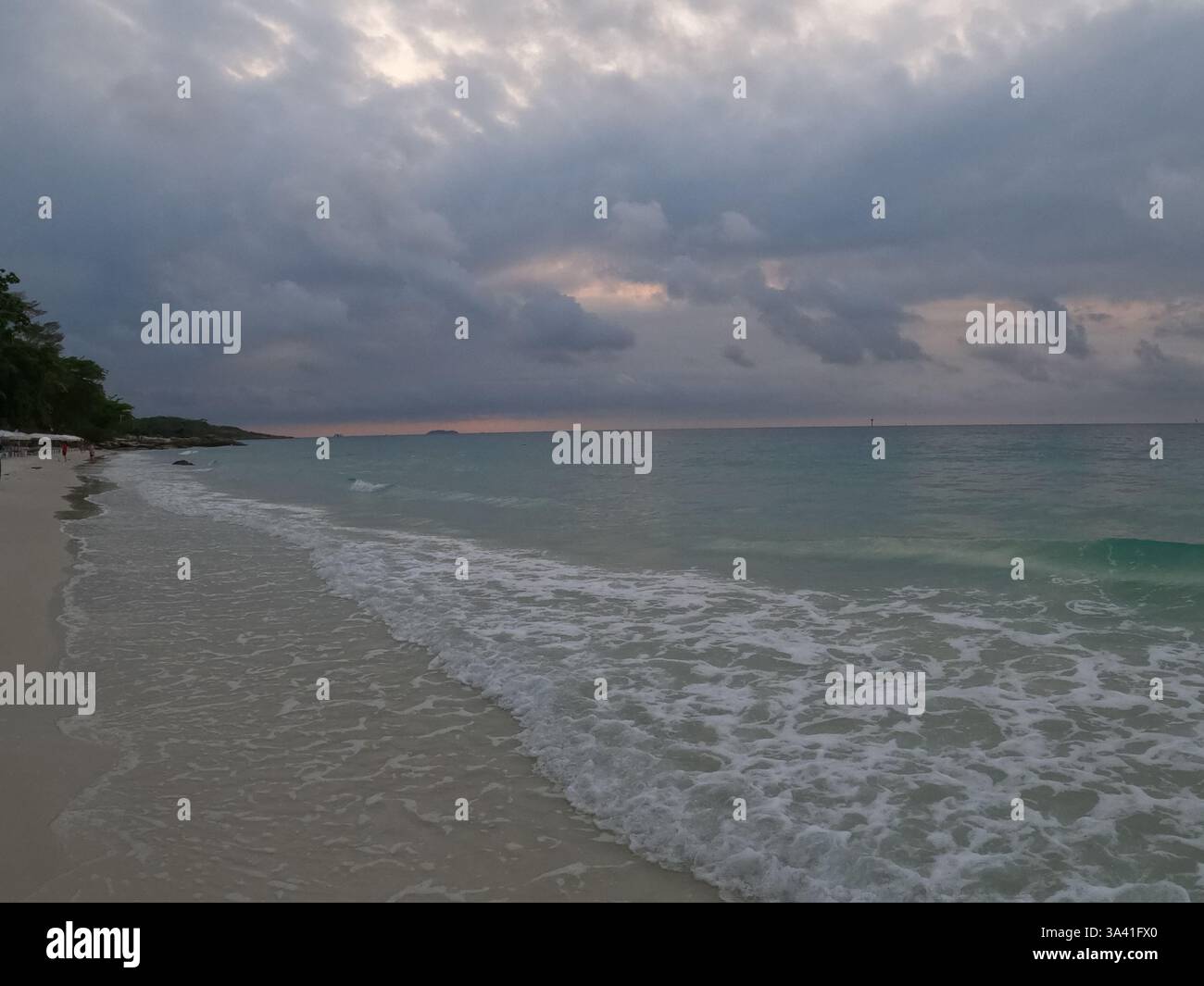 A peaceful evening on the beach, where waves kiss the shore beneath a moody sky. The sound of the ocean and the cool breeze make it a perfect escape. Stock Photo