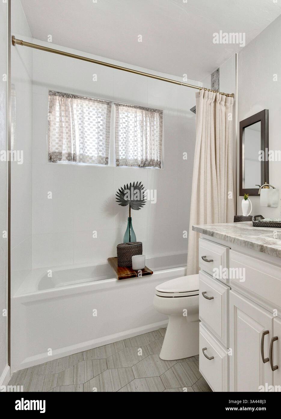 A wellappointed bathroom that includes essential fixtures such as a bathtub, a toilet, a sink, and a mirror for personal grooming Stock Photo