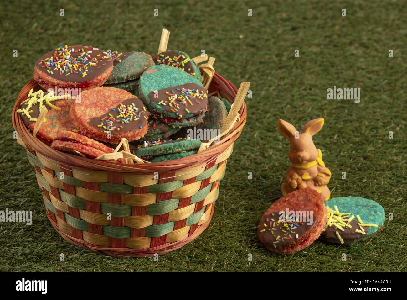Colourful Easter biscuits in a woven basket in a meadow with a rabbit figure Stock Photo