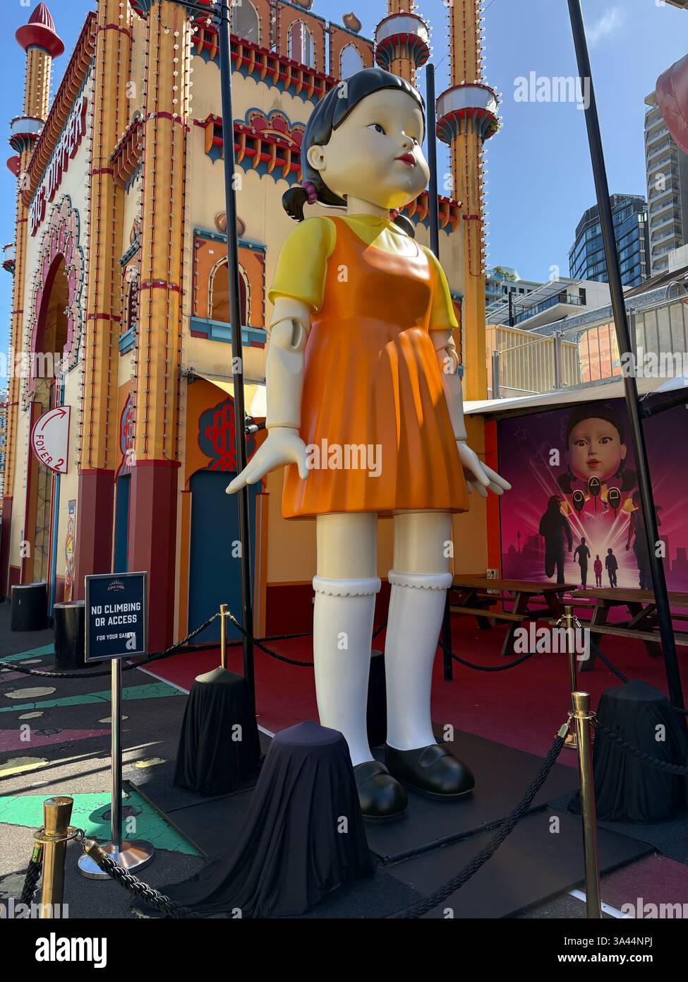 Squid game doll in an orange dress in front of Luna Park in Sydney,  Australia Stock Photo - Alamy