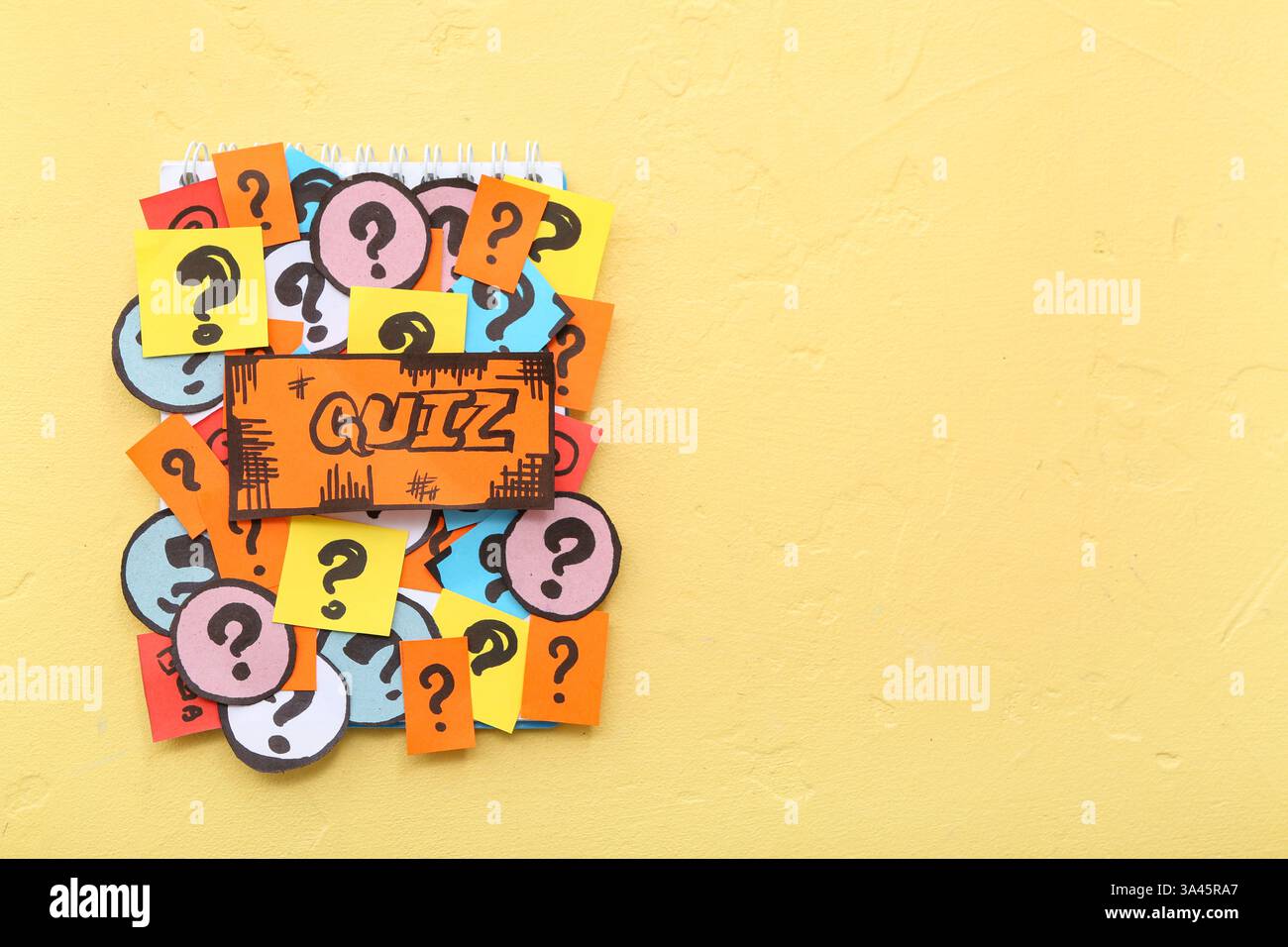 Notebook with quiz card and question marks on yellow background Stock Photo