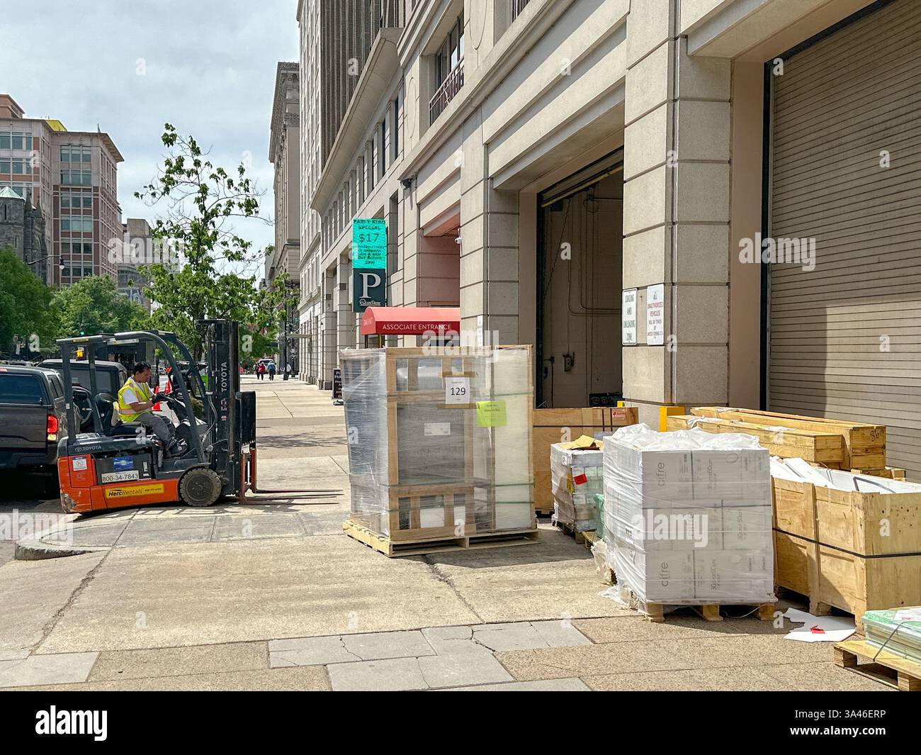 Washington DC, District of Columbia, USA -30 April 2024: Person operating a forklift truck to move pallets of materials into a city office building - Smartphone Captured Stock Image
